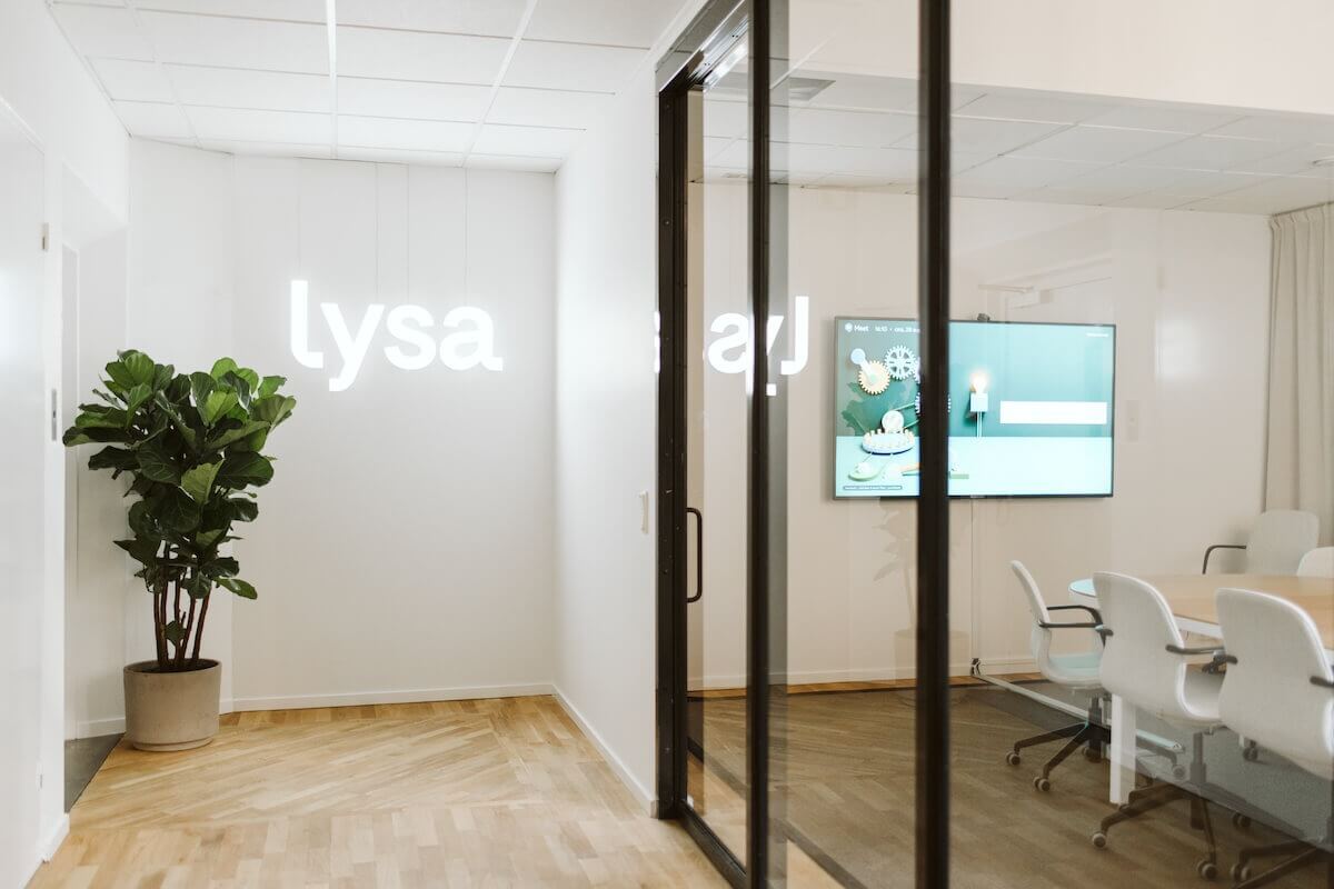 Ein Lysa-Schild erleuchtet die Wand hinter sich im Flur des Büros