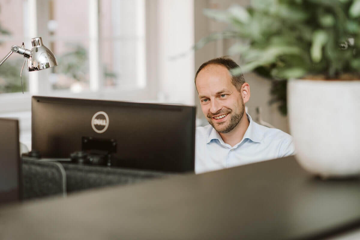 Lysas CEO sitzt an seinem Computer, schaut hoch und lächelt